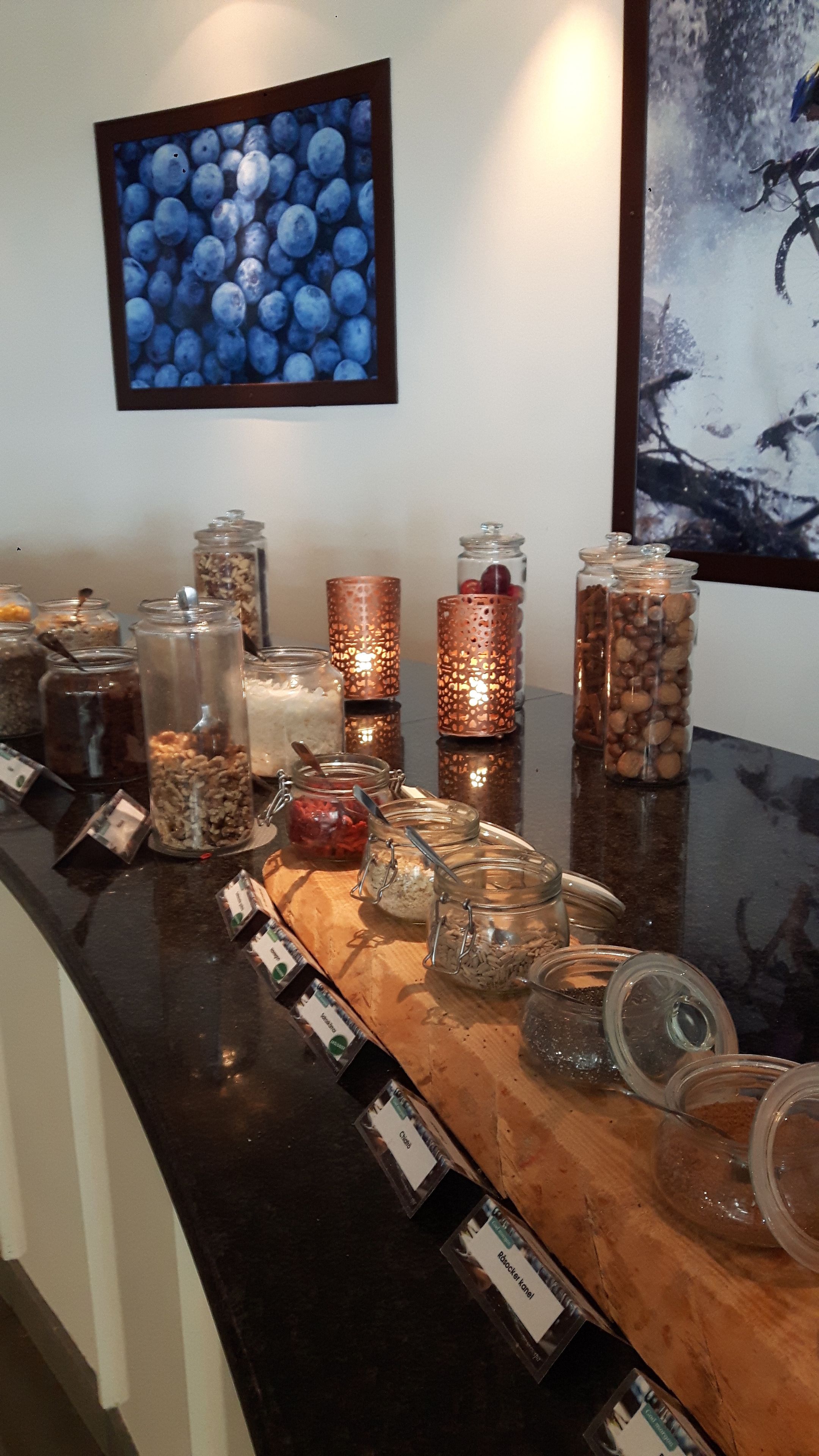 A food display with various jars labeled with ingredients, a framed picture of blueberries, and a candle holder.
