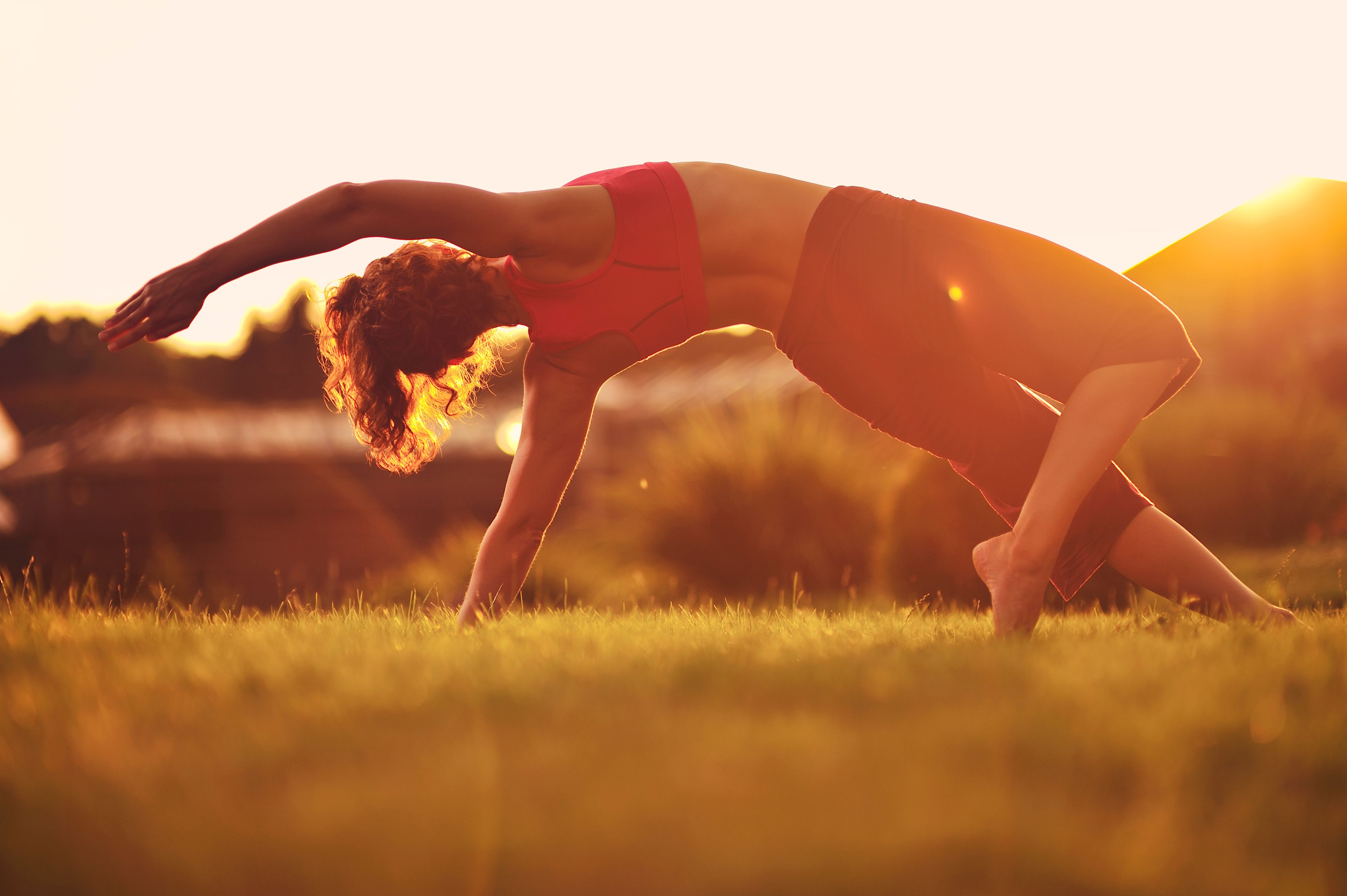 A person performing a yoga pose in a grassy outdoor area.