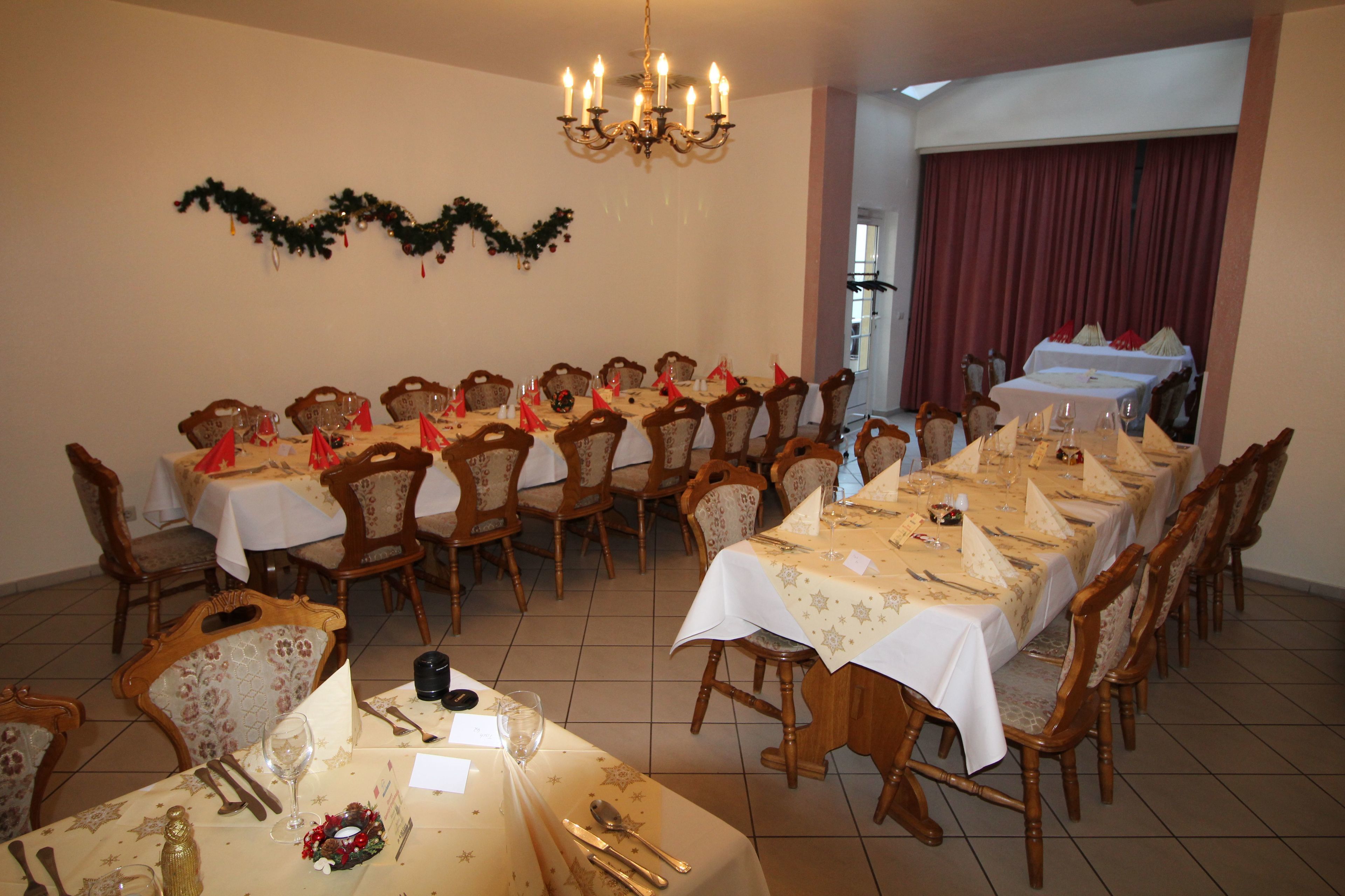 Un comedor con mesas redondas, sillas de madera y un candelabro.