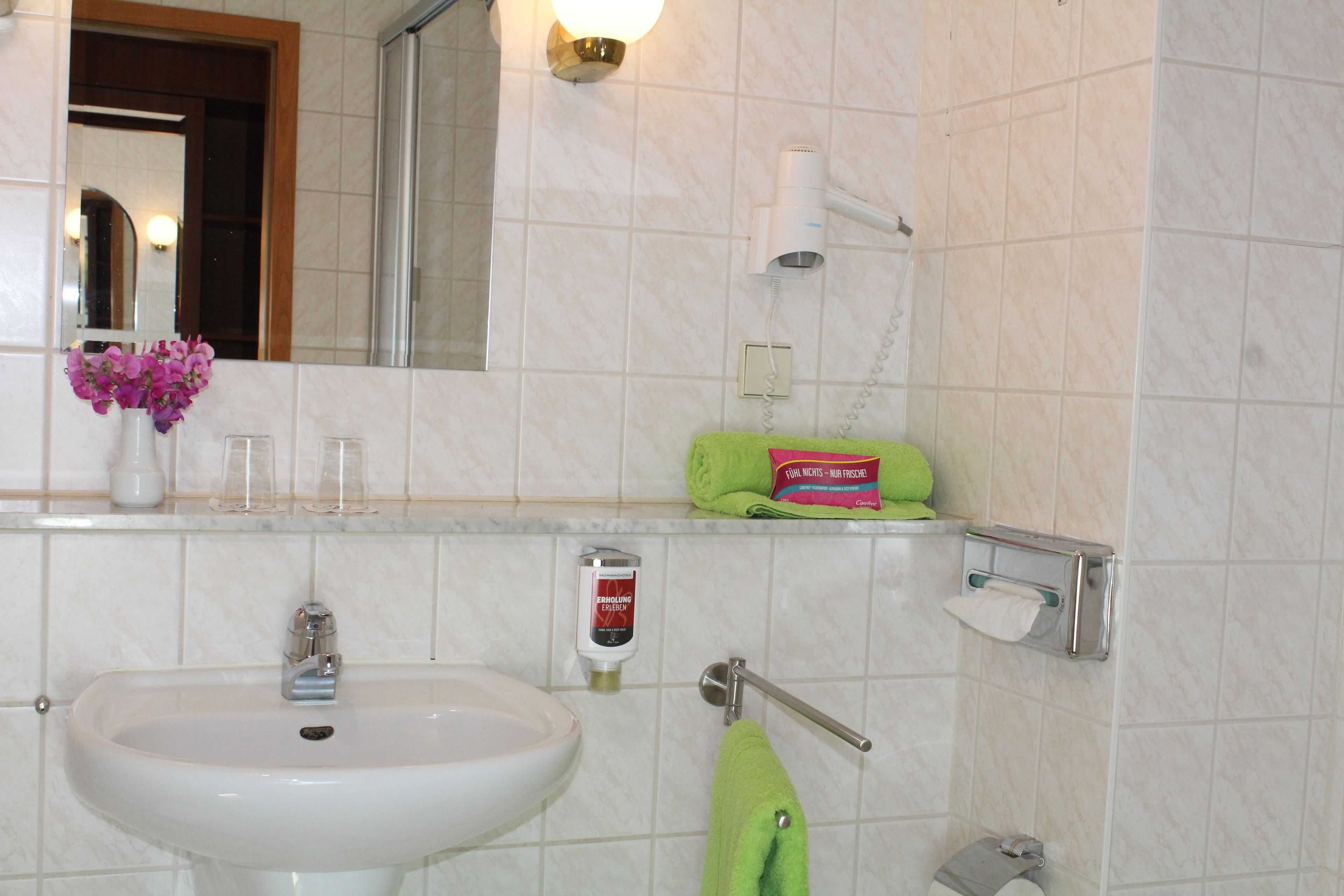 A bathroom with a sink, mirror, towel rack, and toiletries.