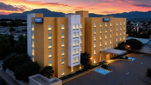 A multi-story hotel with a flat facade, multiple windows, and a parking lot with marked spaces. - City Express by Marriott Saltillo Sur (Saltillo)