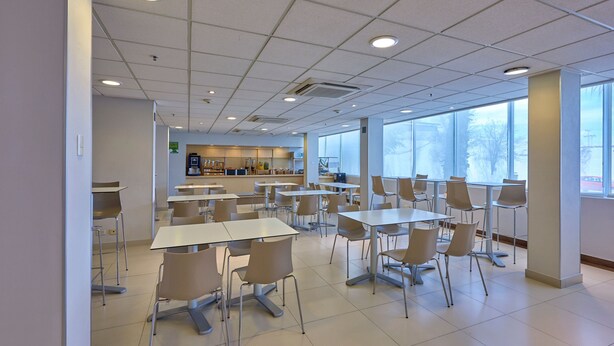 Una cafetería amplia con mesas y sillas dispuestas para comer.