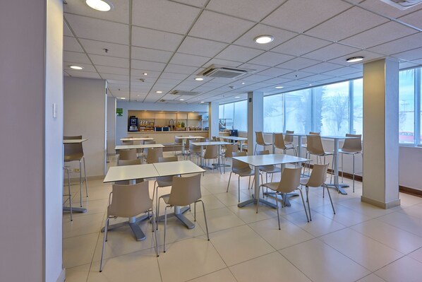 Une cafétéria spacieuse, avec des tables et des chaises disposées pour accueillir les clients.