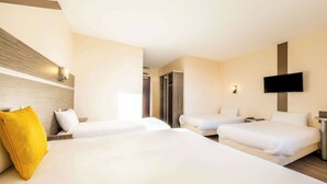 Una camera d'albergo con due letti, una TV a muro e una testiera in legno.