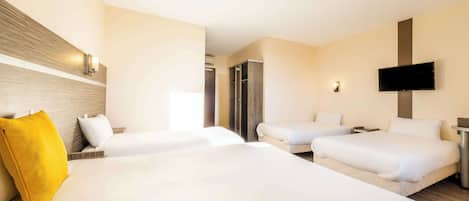 A hotel room with two beds, a TV mounted on the wall, and a wooden headboard.