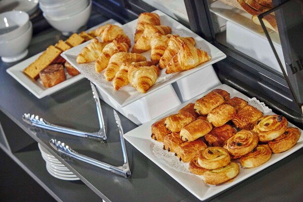 A buffet with various pastries and bread.