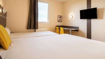 A hotel room with two beds, a desk, a flat-screen TV, and a window with curtains.