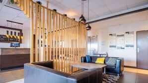Una hall moderna con reception, area salotto e un pannello in legno.