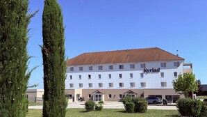 A hotel with a white facade, multiple windows, and a red-tiled roof. - Kyriad Dijon Sud - Longvic (Longvic)