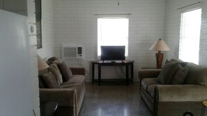 A living room with two sofas, a TV on a stand, and a lamp. - Astor Bridge Marina & Motel (Astor)