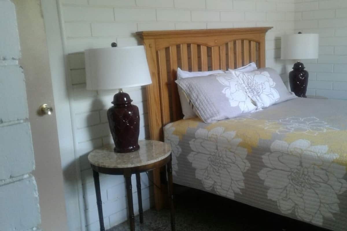 A bedroom with a wooden headboard, two bedside lamps, a round table, and a floral bedspread.