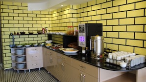 Uma cozinha com azulejos de parede amarelos, eletrodomésticos de aço inoxidável e alimentos organizados.