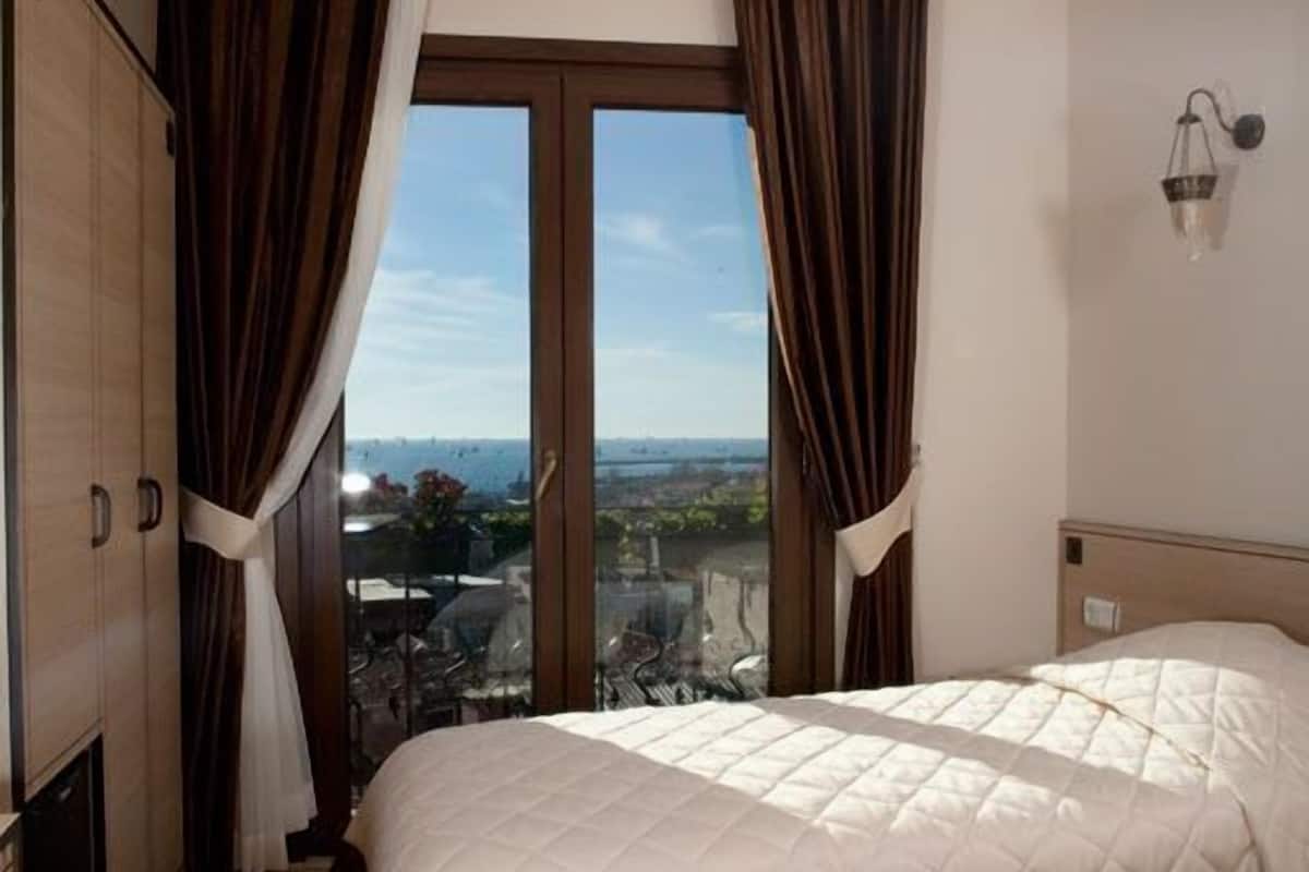 Hotellihuone, jossa on suuri sänky, näköala kaupunkiin ja parveke.