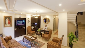 Uma sala de estar espaçosa com sofá, cadeiras, mesa de centro, televisão e escada.
