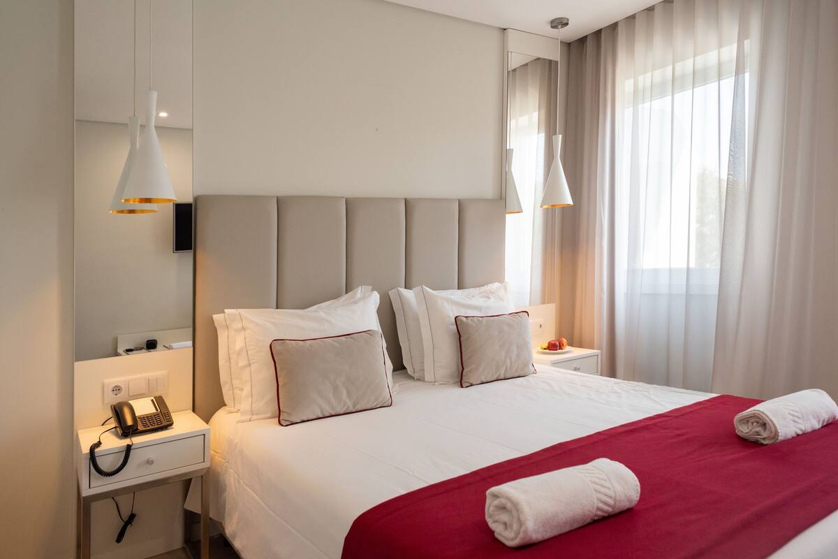 Et hotelværelse med seng, sengeborde, telefon og et spejl.