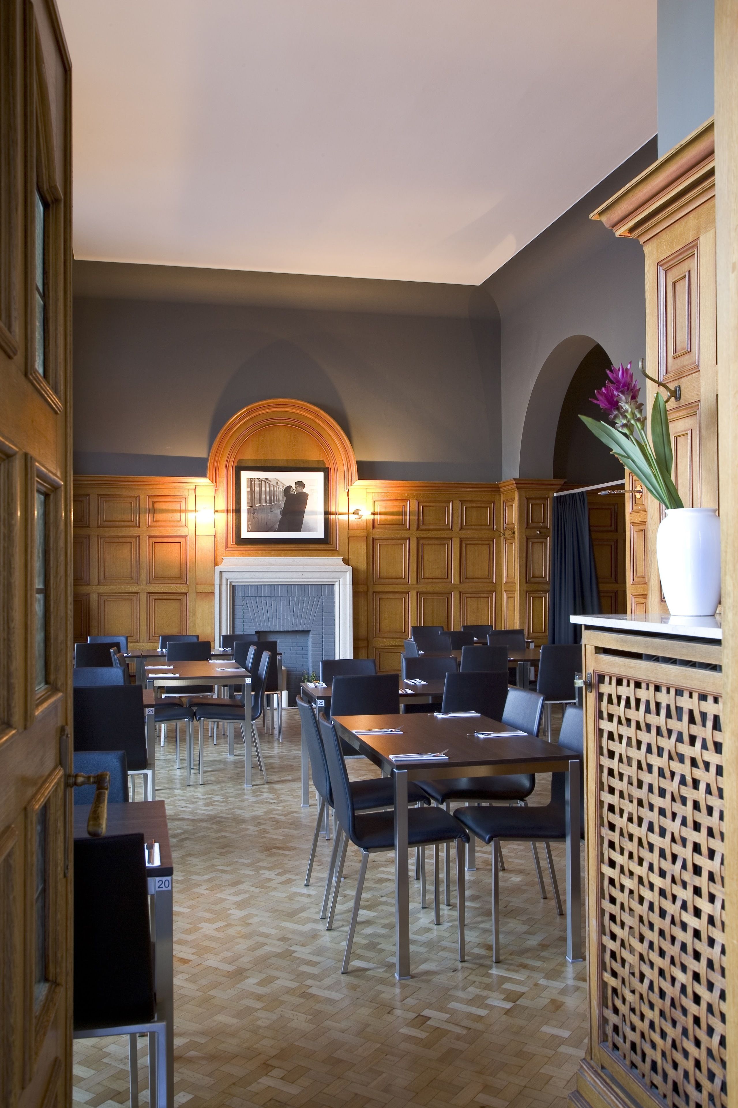 A restaurant with wooden paneling, a fireplace, and multiple tables and chairs.