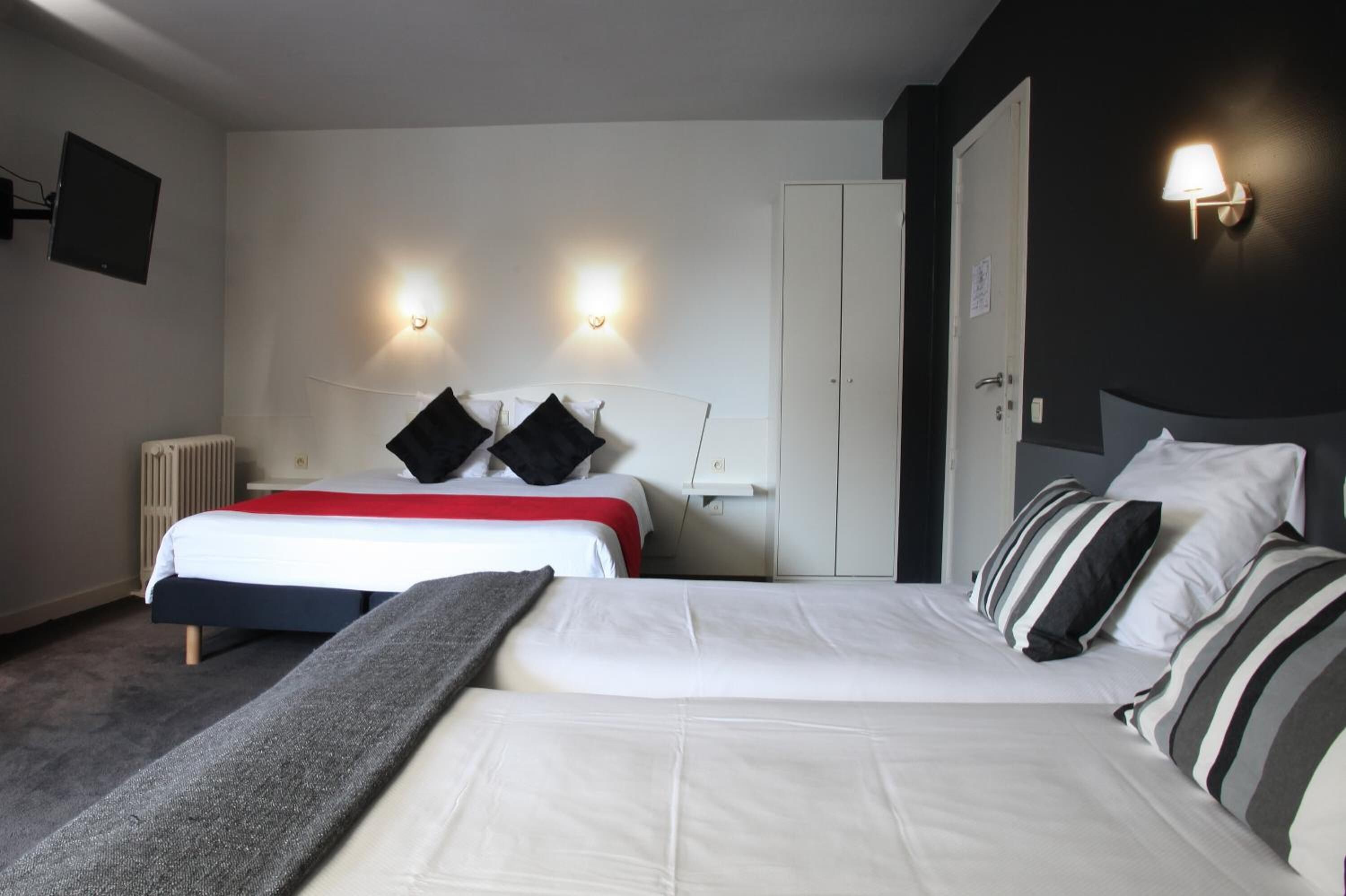 Habitación de hotel con cama doble, dos mesitas de noche, un radiador, una puerta y dos lámparas fijadas a la pared.