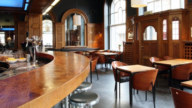 A spacious restaurant with high ceilings, wooden beams, and large arched windows allowing natural light. - Hotel La Royale (Leuven)