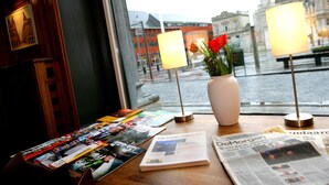 A table with magazines, newspapers, and a vase with flowers. - Hotel La Royale (Leuven)