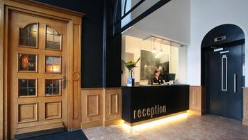 A reception area with a wooden door, a black reception desk, and a receptionist.