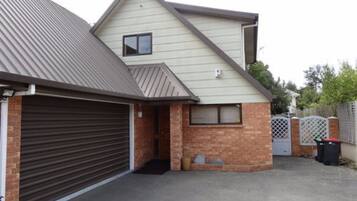 A two-story house with a garage, brick foundation, and a metal roof.