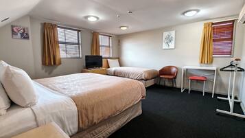 A hotel room with two beds, a desk, a chair, a TV, and a wardrobe.