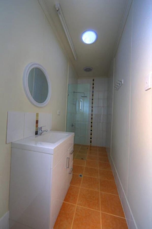 A narrow hallway with a bathroom on the left, featuring a sink and mirror.