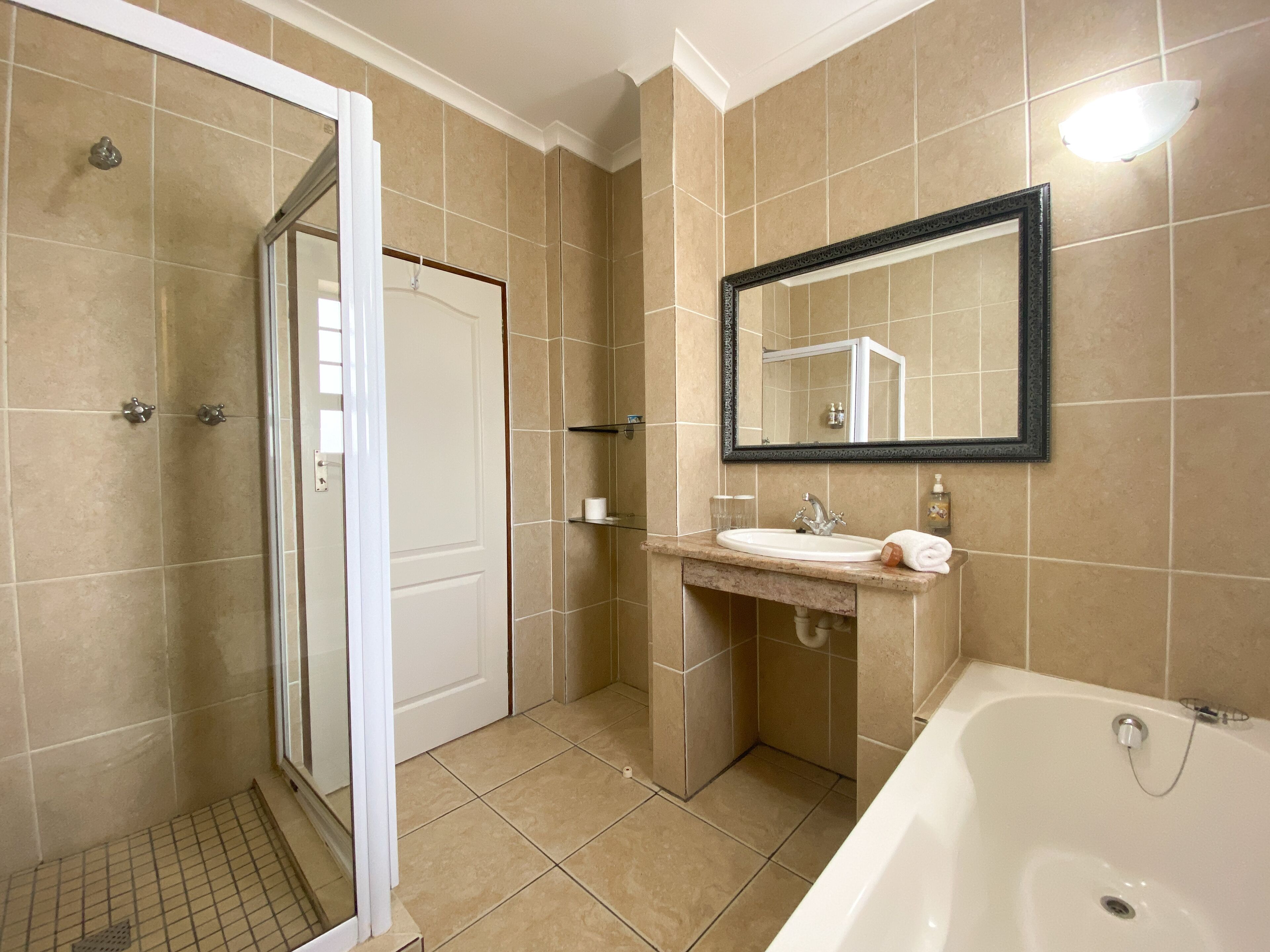 Een badkamer met een douche, wastafel en bad.