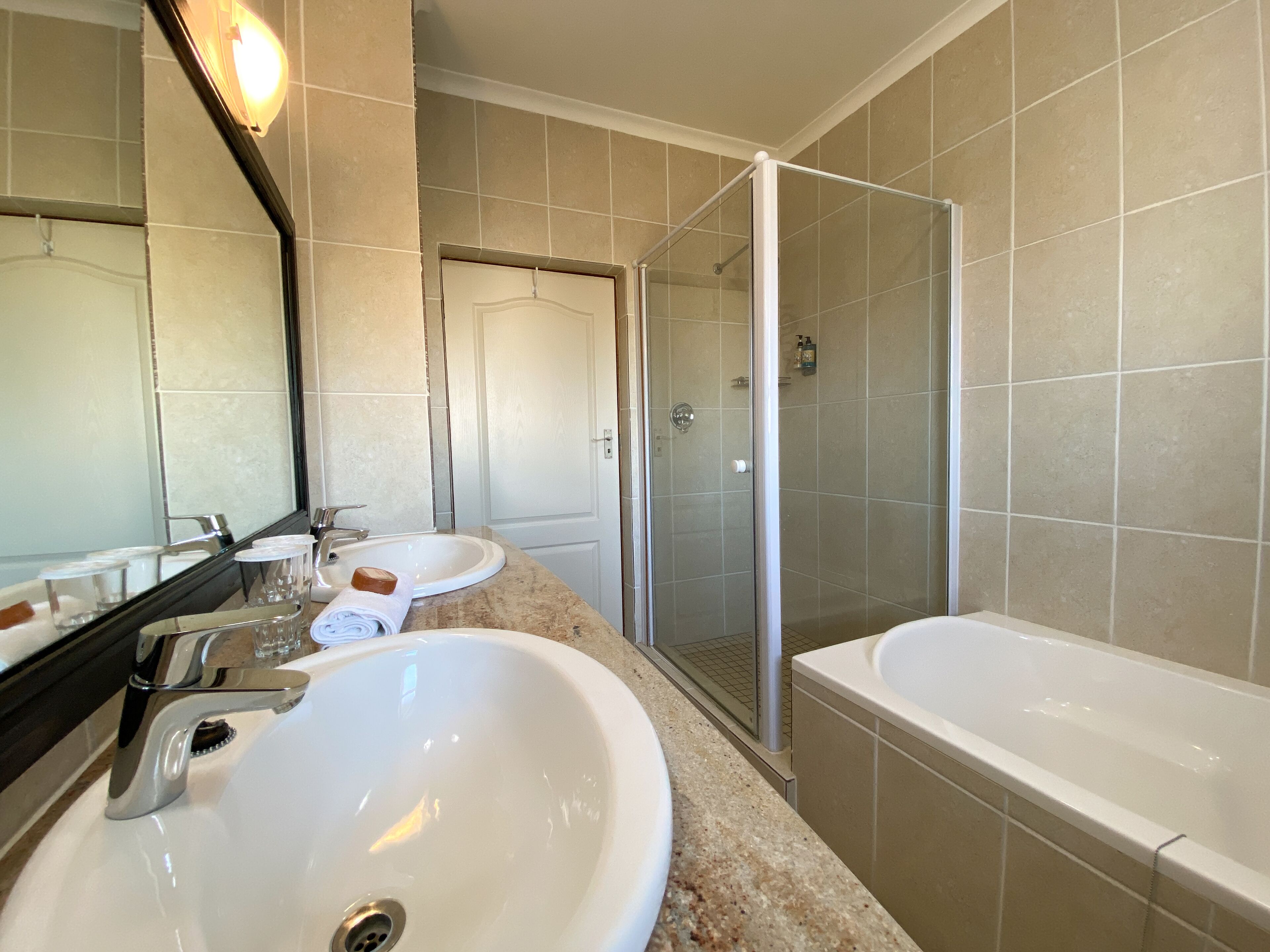 A bathroom with two sinks, a large bathtub, and a glass-enclosed shower.