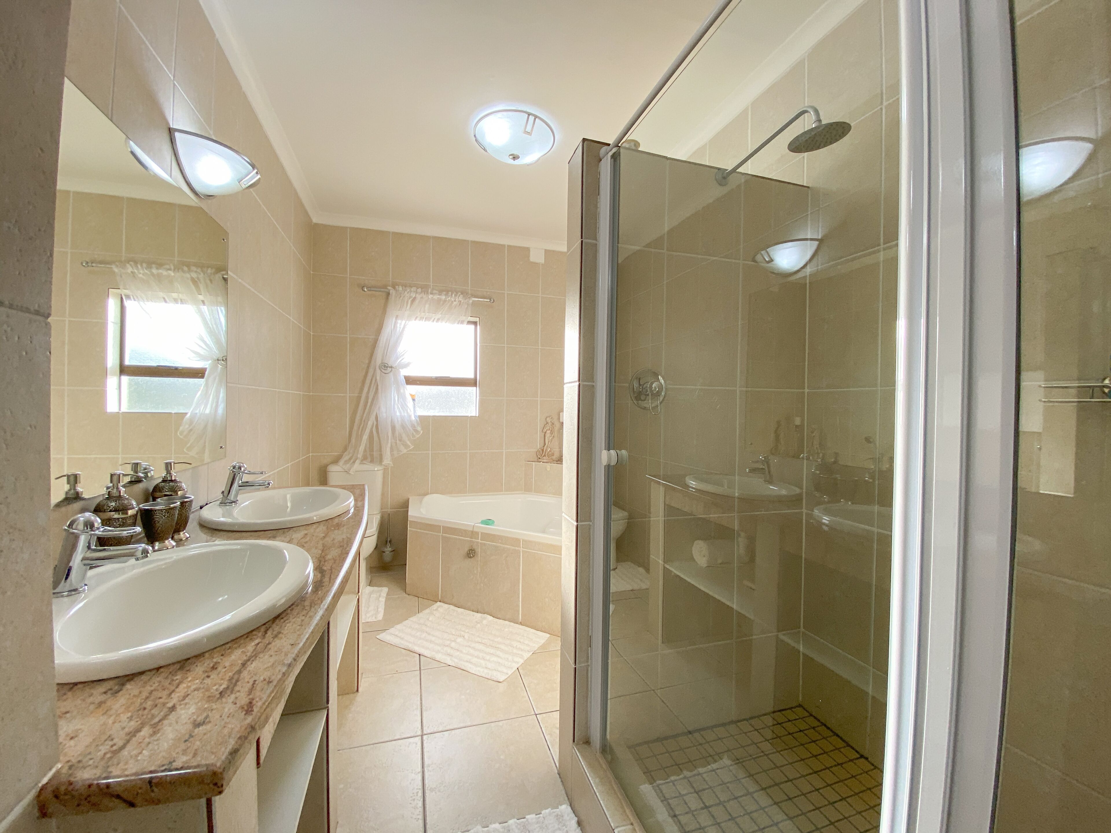 A bathroom with two sinks, a bathtub, and a glass-enclosed shower.