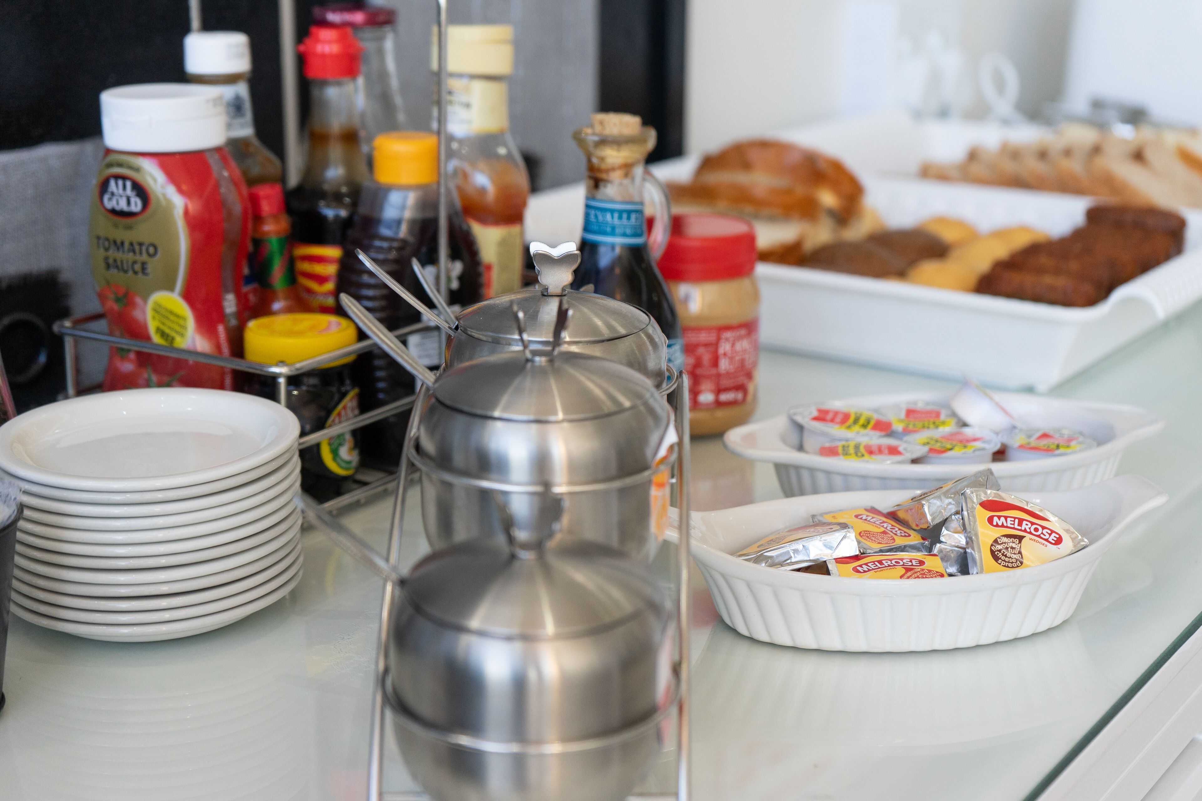 A breakfast buffet with various food items, condiments, and a coffee pot.