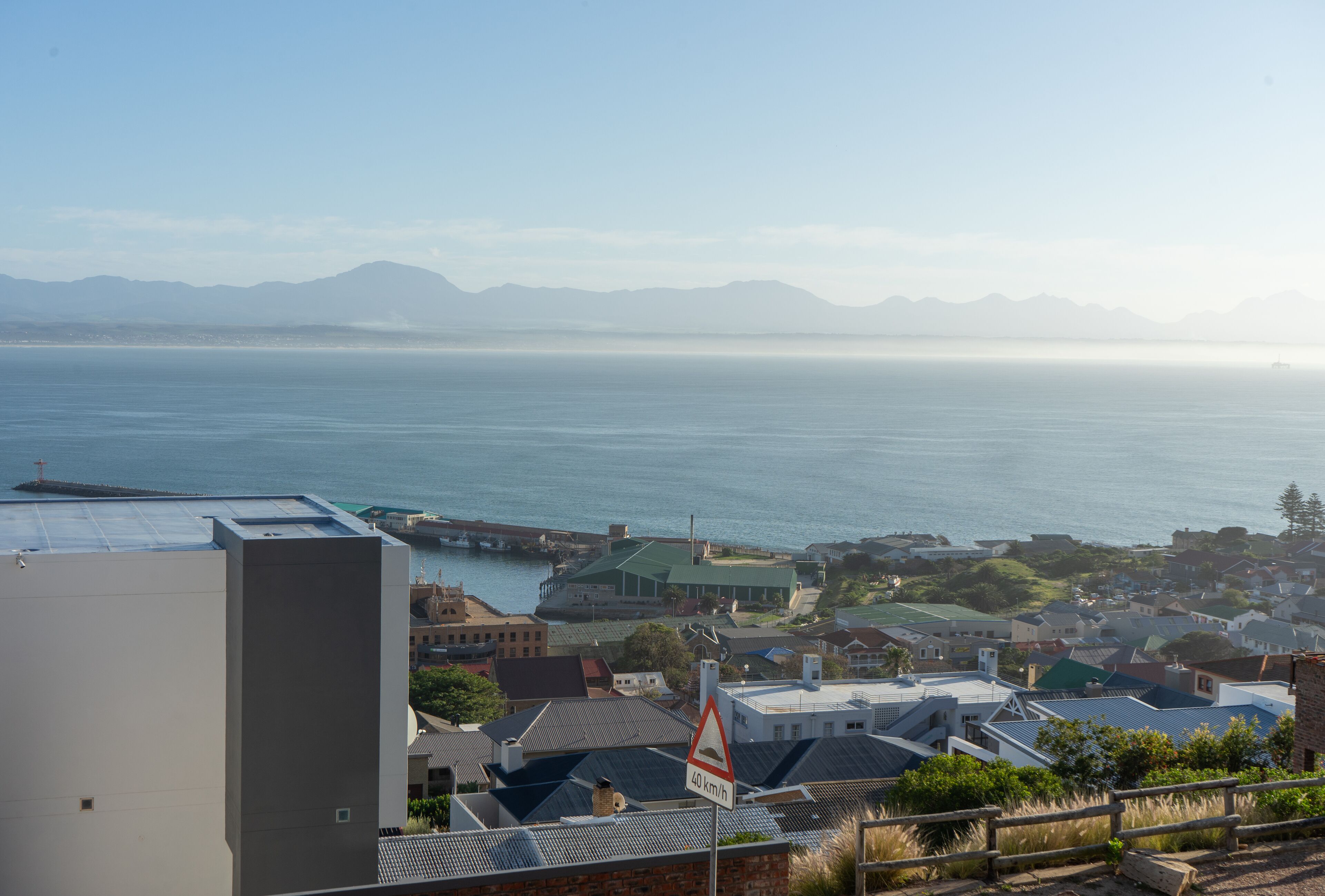 A coastal town with a view of the sea and mountains in the distance.