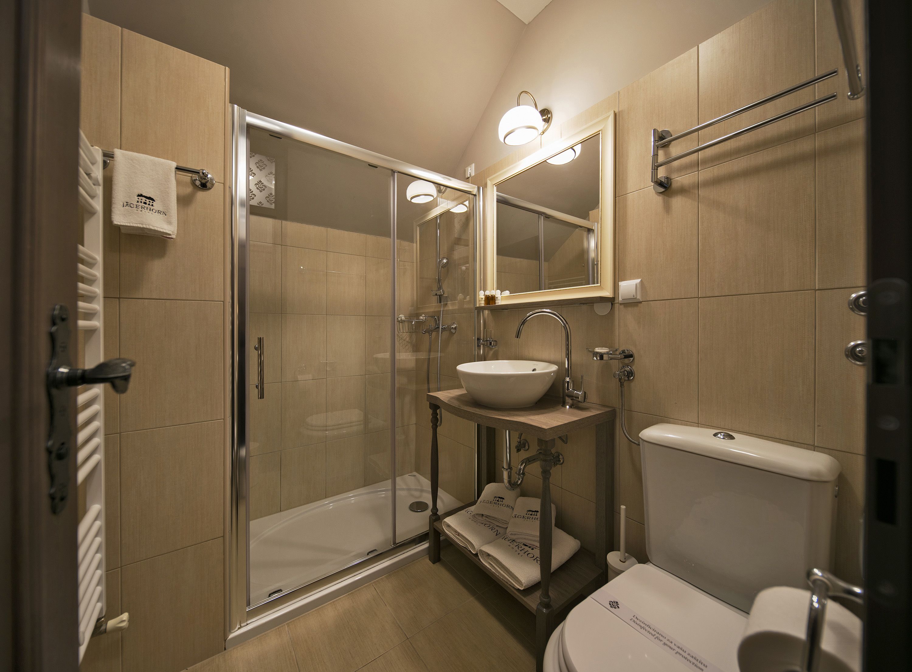 A modern bathroom with a glass-enclosed shower, a sink with a mirror above, and a toilet.