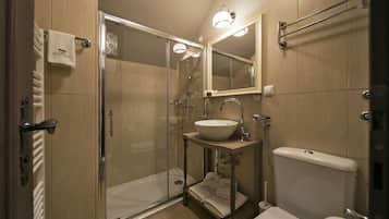 A modern bathroom with a glass-enclosed shower, a sink with a mirror above, and a toilet.