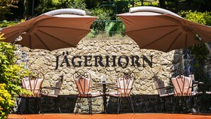 A stone wall with the name "Jägerhorn" and outdoor seating with umbrellas. - Hotel Jägerhorn (Zagreb)