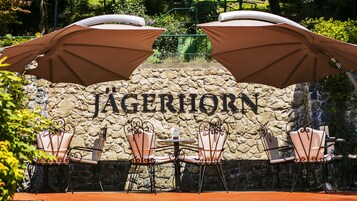 Een stenen muur met de naam "Jägerhorn" en terras met parasols.