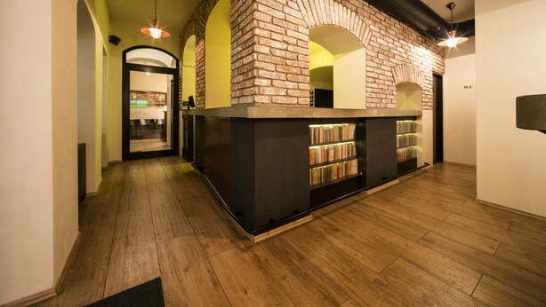 Un vestíbulo con pared de ladrillo, estanterías y suelo de madera.
