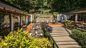 A courtyard with outdoor seating, a stone wall with 'JAGERTHORN' signage, and lush greenery. - Hotel Jägerhorn (Zagreb)
