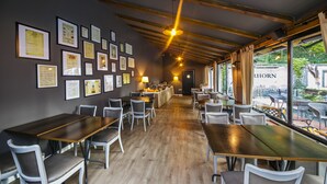 Un restaurante con mesas y sillas largas, certificados enmarcados en la pared y vistas al exterior.