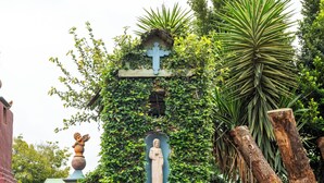 Un edificio con puerta de madera, una estatua y una cruz.