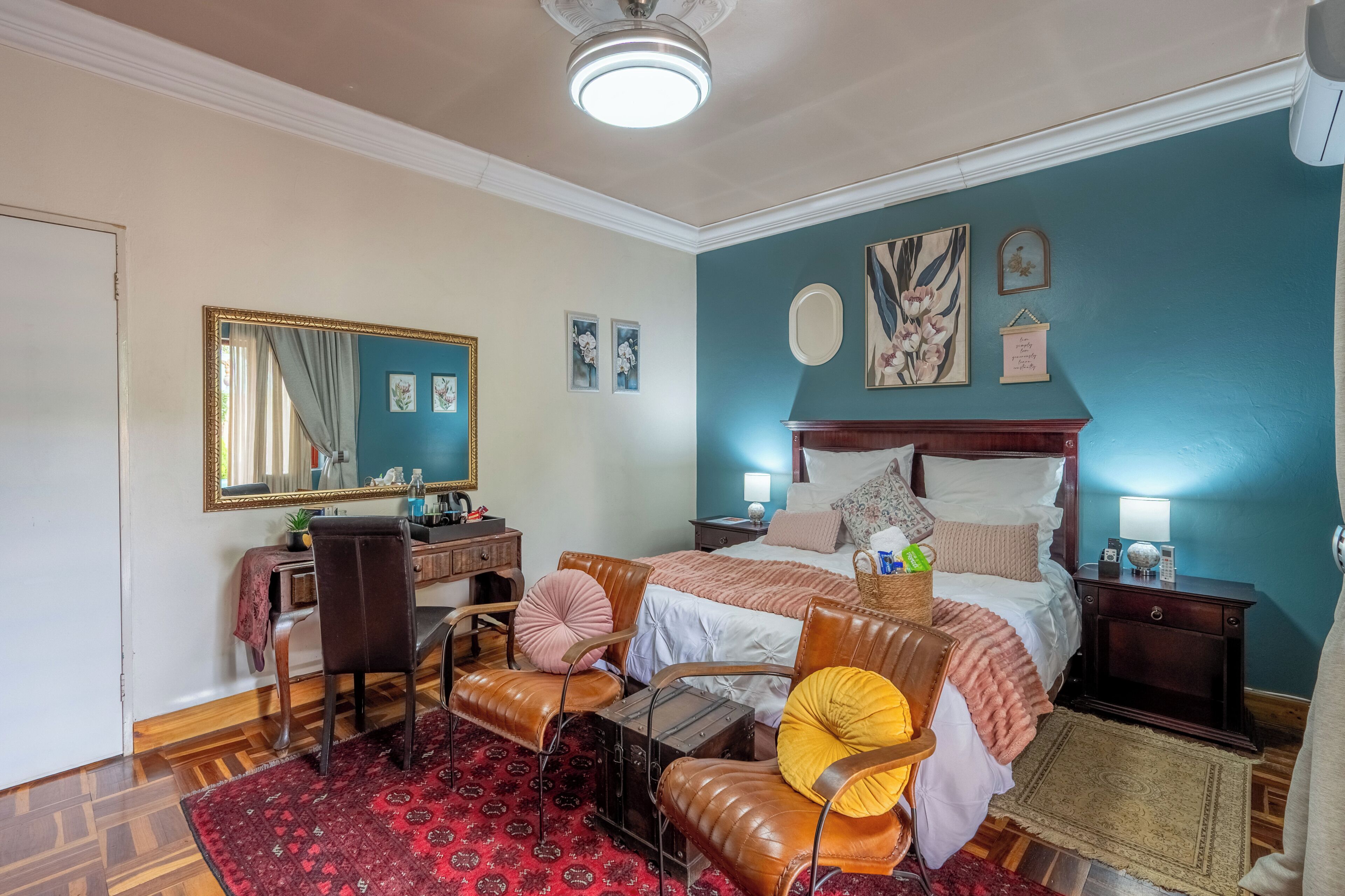 Quarto com cama, escrivaninha, cadeira, espelho e cómoda.