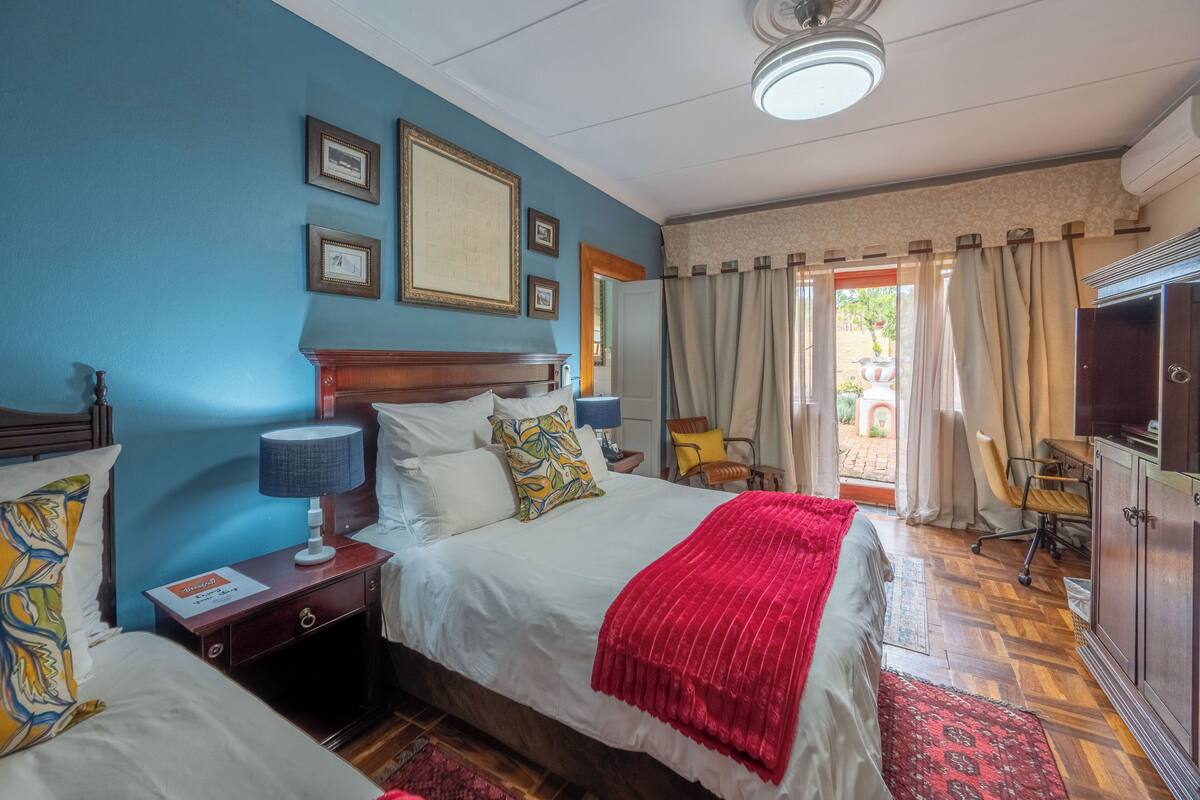 Quarto de hotel com cama, mesas de cabeceira, abajur, televisão e vista para o exterior.