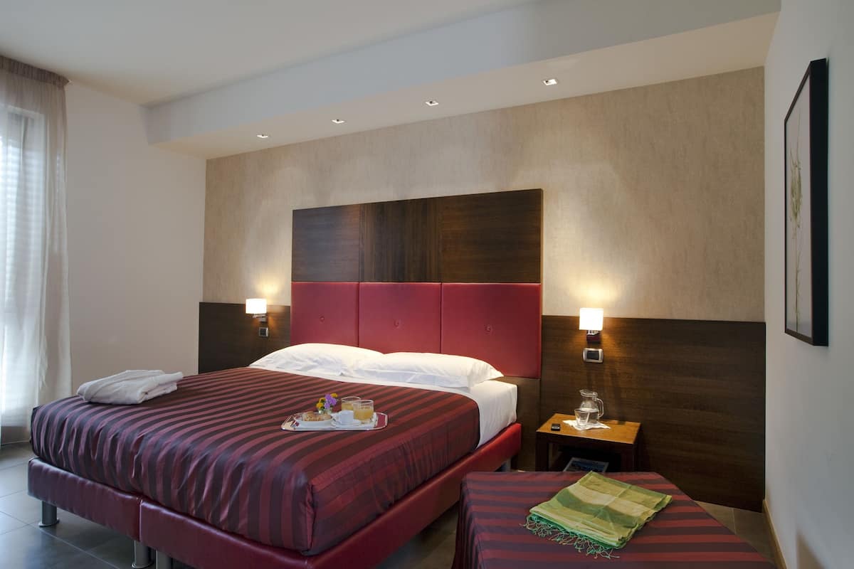 A hotel room with a large bed, two bedside tables, and a small table with a tray of breakfast.