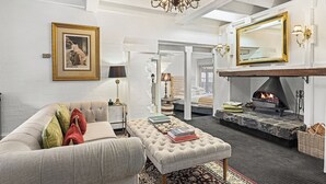 A living room with a fireplace, a sofa, an ottoman, and a large mirror. - The Loft In The Mill Boutique Accommodation (Olinda)