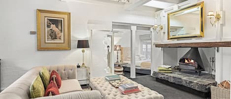 A living room with a fireplace, a sofa, an ottoman, and a large mirror.