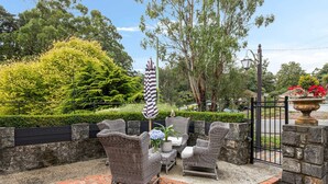 A patio area with wicker furniture, a flag, and a stone wall. - The Loft In The Mill Boutique Accommodation (Olinda)