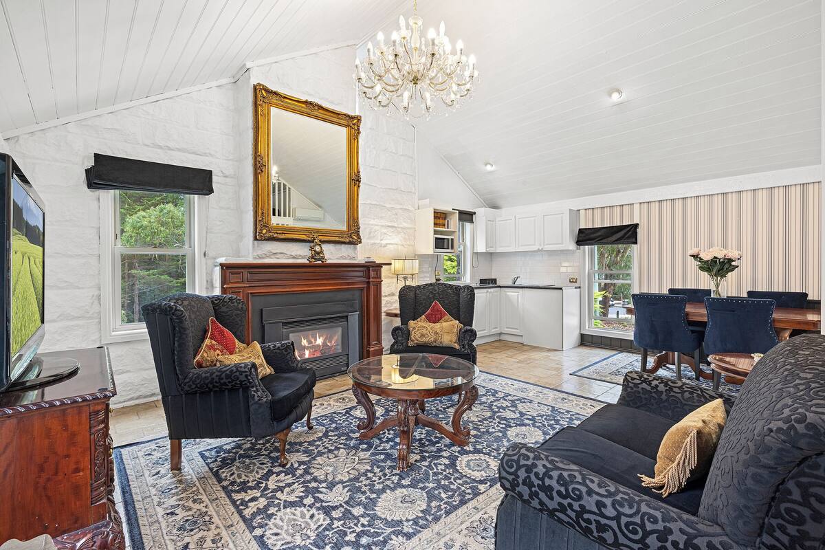 A spacious living room with a fireplace, comfortable seating, and a large mirror.
