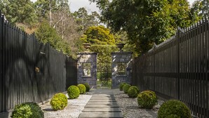 A pathway leading to a gated entrance with stone pillars and a gravel surface. - The Loft In The Mill Boutique Accommodation (Olinda)