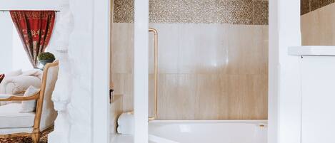 Une salle de bain avec une baignoire, une douche et un mur recouvert de carreaux blancs ornés de motifs décoratifs.