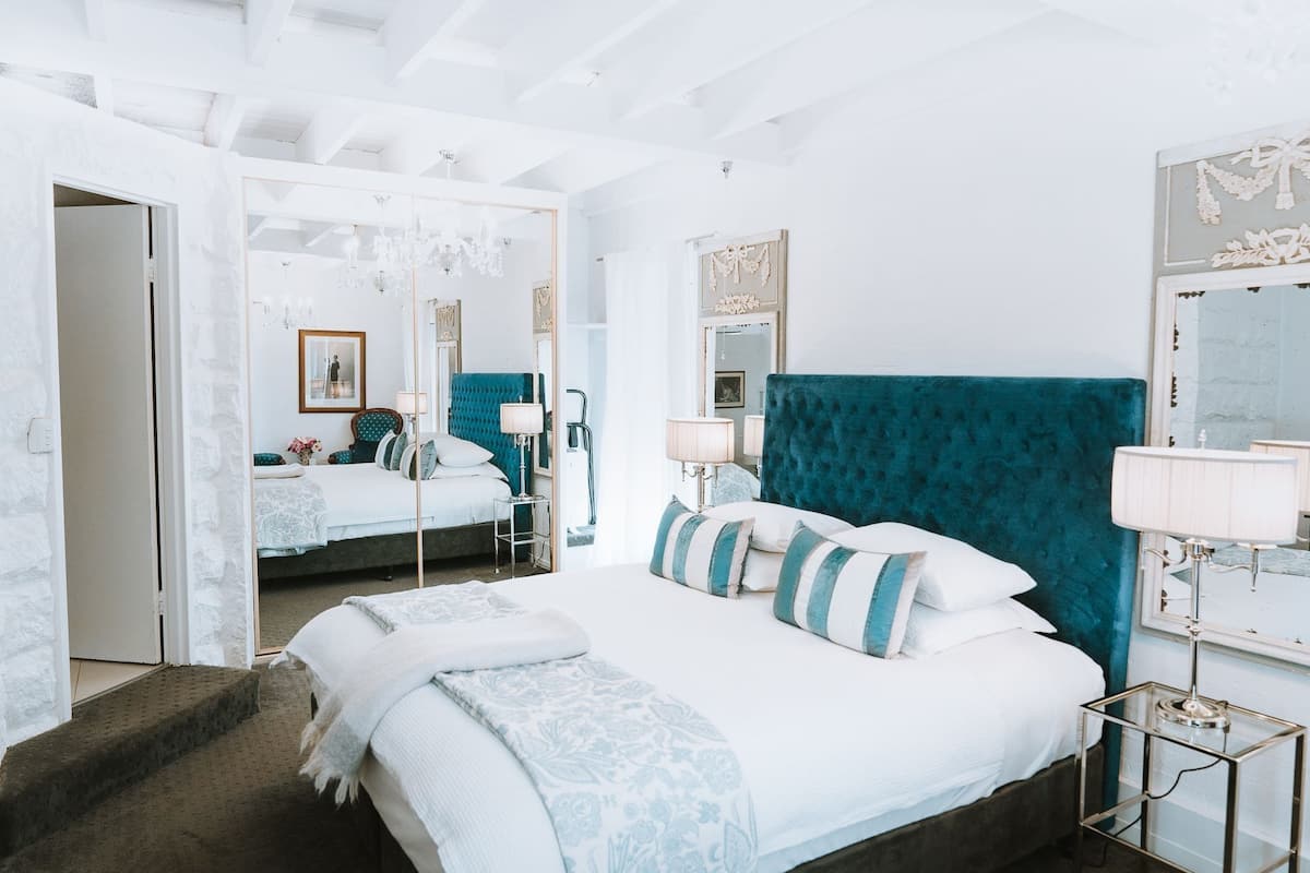 A modern bedroom with a large bed, a mirror, and a chandelier.